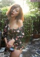 A woman in a black and red floral dress posing for a picture.