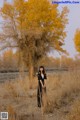 A woman standing in a field next to a tree.